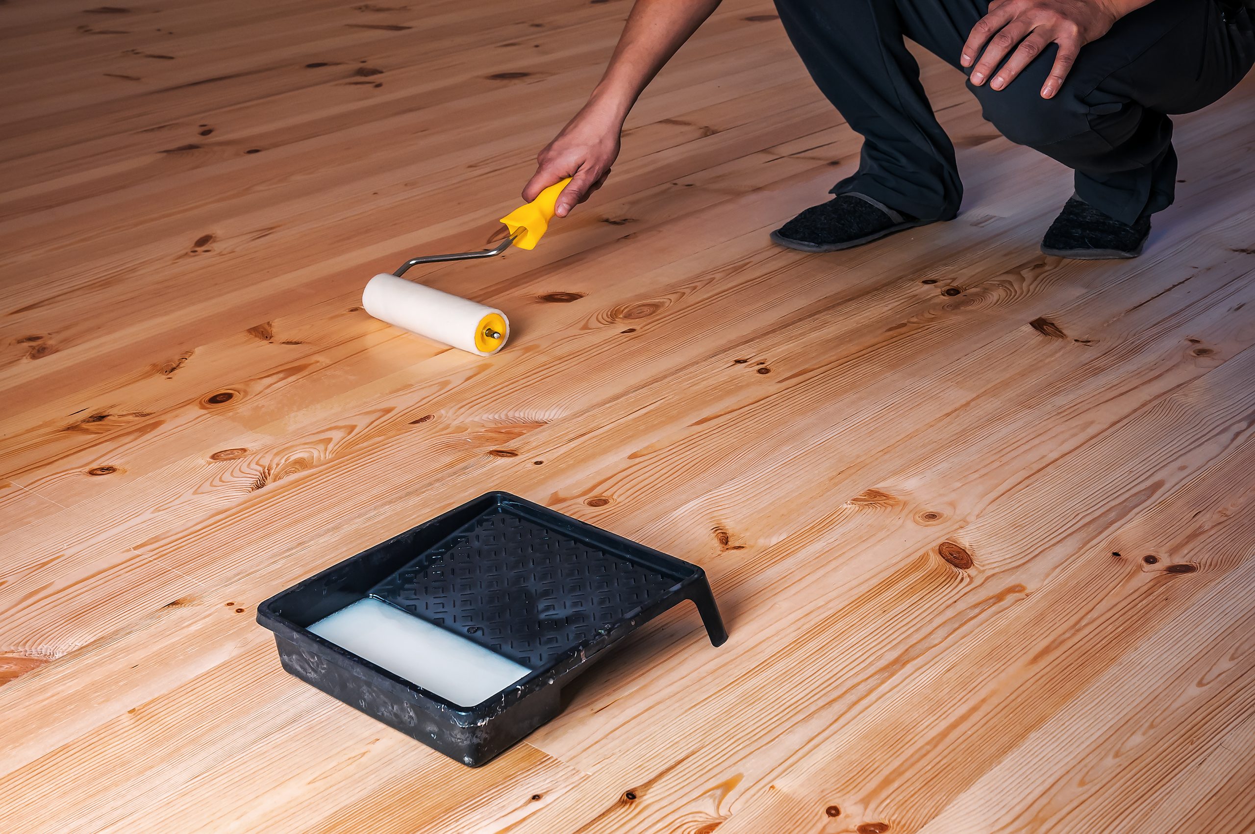 Wood Floor Sanding in Walthamstow on pine softwood floorboards, with a contractor applying a clear roller finish after sanding to reveal a smooth, bright surface.