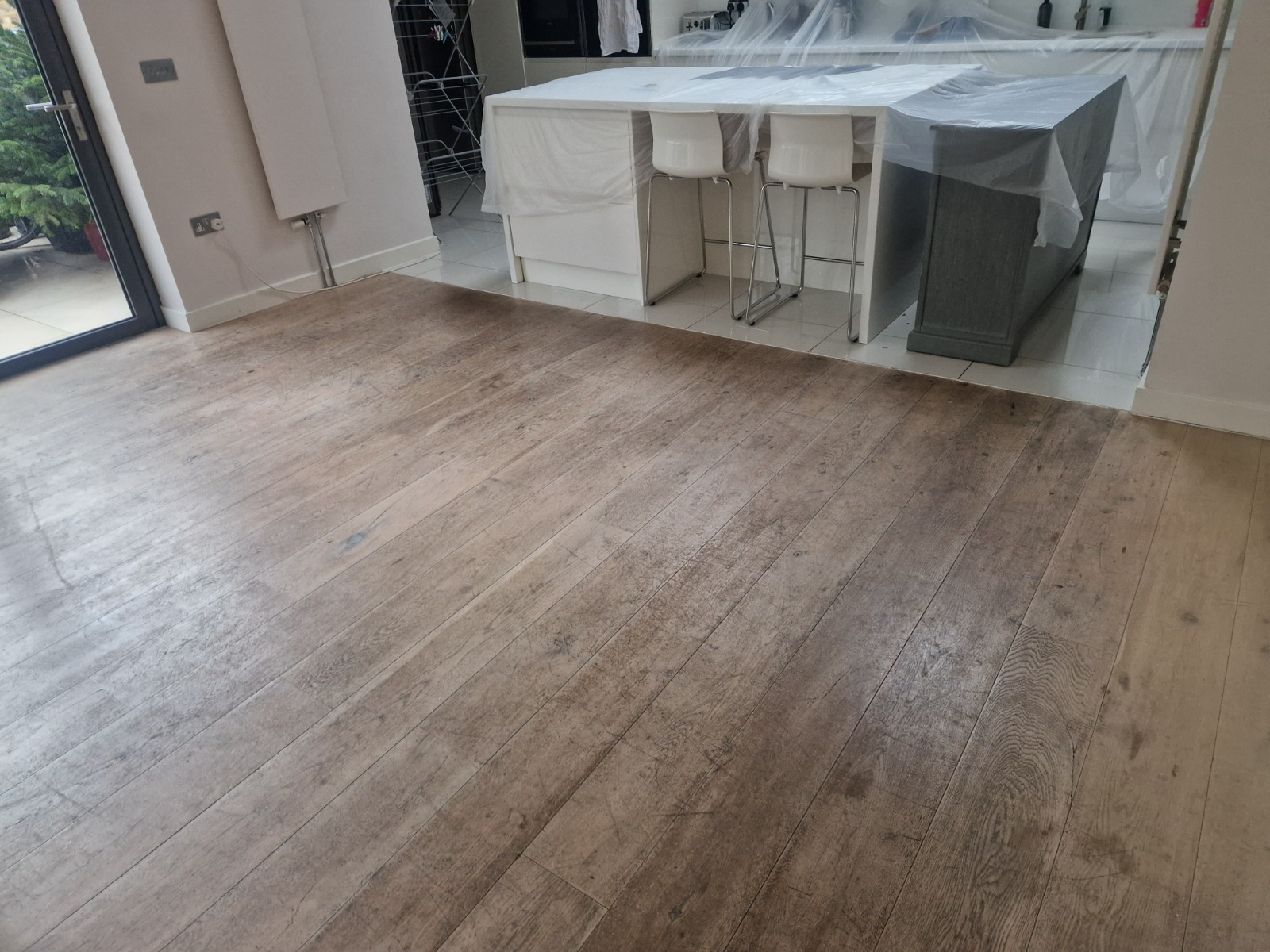 Hardwood Floor Refinishing in Walthamstow showing an oak wide plank hardwood floor before restoration in a modern kitchen and dining area