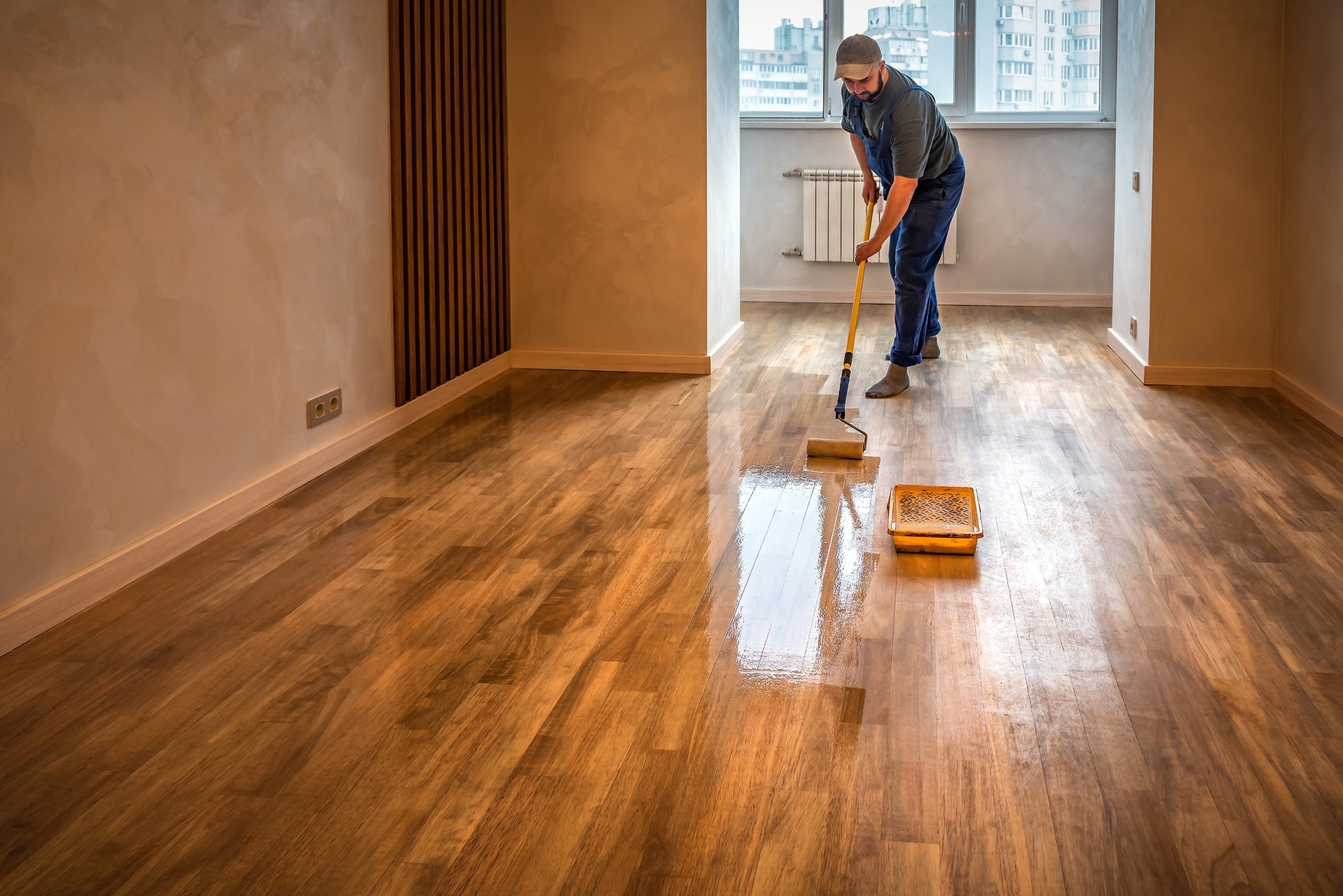 Hardwood Floor Refinishing in Walthamstow with sealant being applied to a solid oak plank hardwood floor in a modern interior