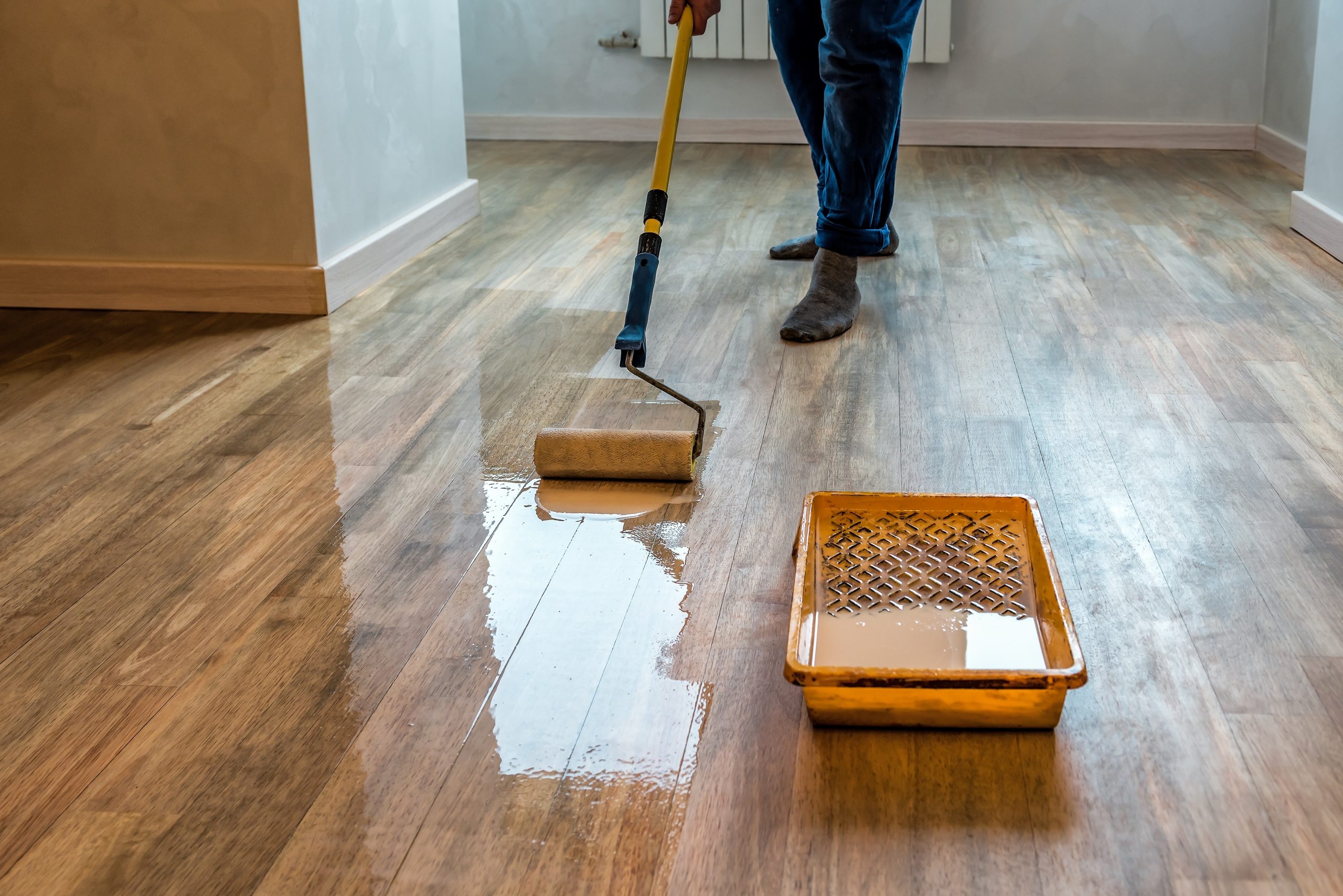 Hardwood Floor Refinishing in Walthamstow with sealant being applied to a walnut hardwood plank floor for a smooth renewed finish